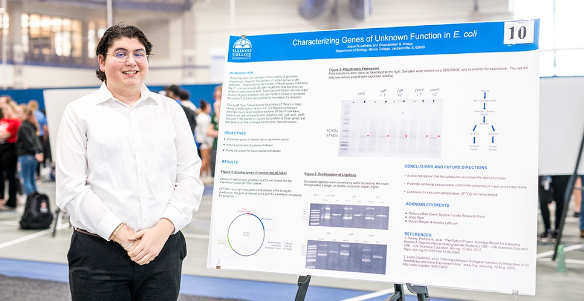 Student poses with his presentation poster