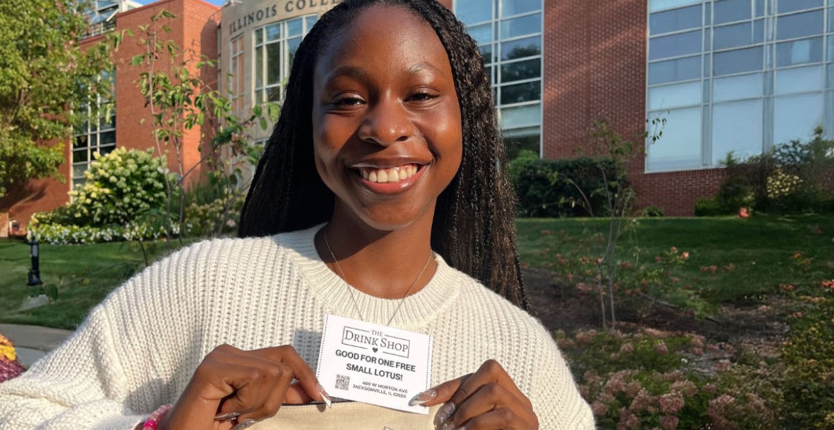 Odosa Imasuen ’25 posing with a free drink voucher from The Drink Shop.