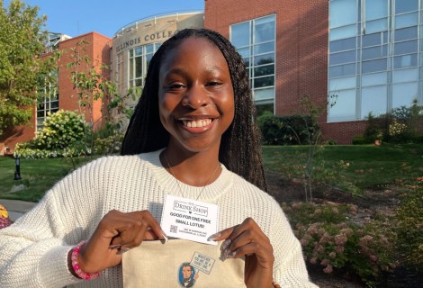 Odosa Imasuen ’25 posing with a free drink voucher from The Drink Shop.