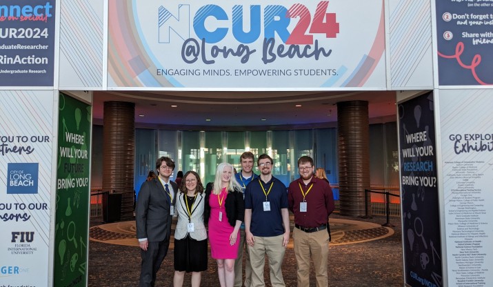 IC students who presented at NCUR standing underneath the NCUR 2024 banner