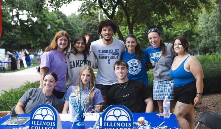Illinois College students smiling and posing at a table 
